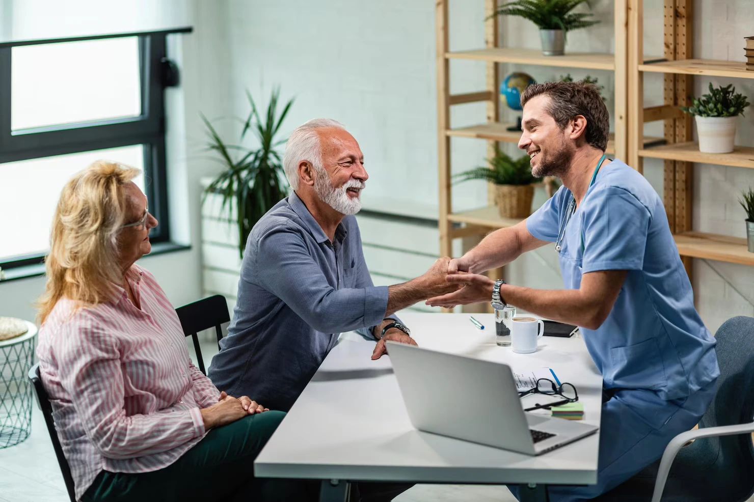 Clinician greeting a senior patient and his wife at an appointment